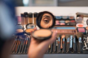 Woman looking in compact mirror before doing make-up