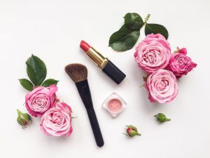 Decorative flat lay composition with cosmetics and flowers. Flat lay, top view on white background